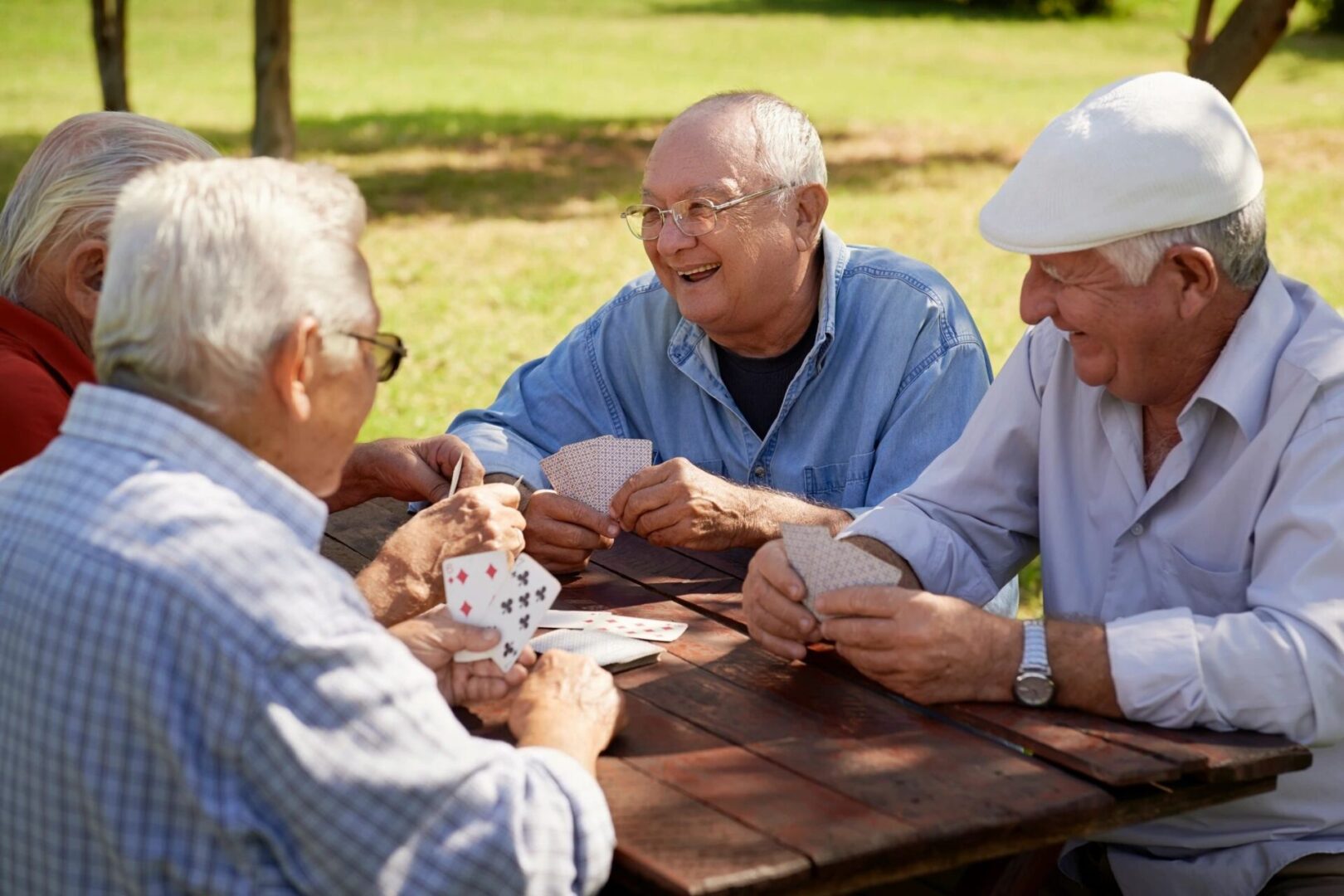 Three older men sitting at a table playing cards.